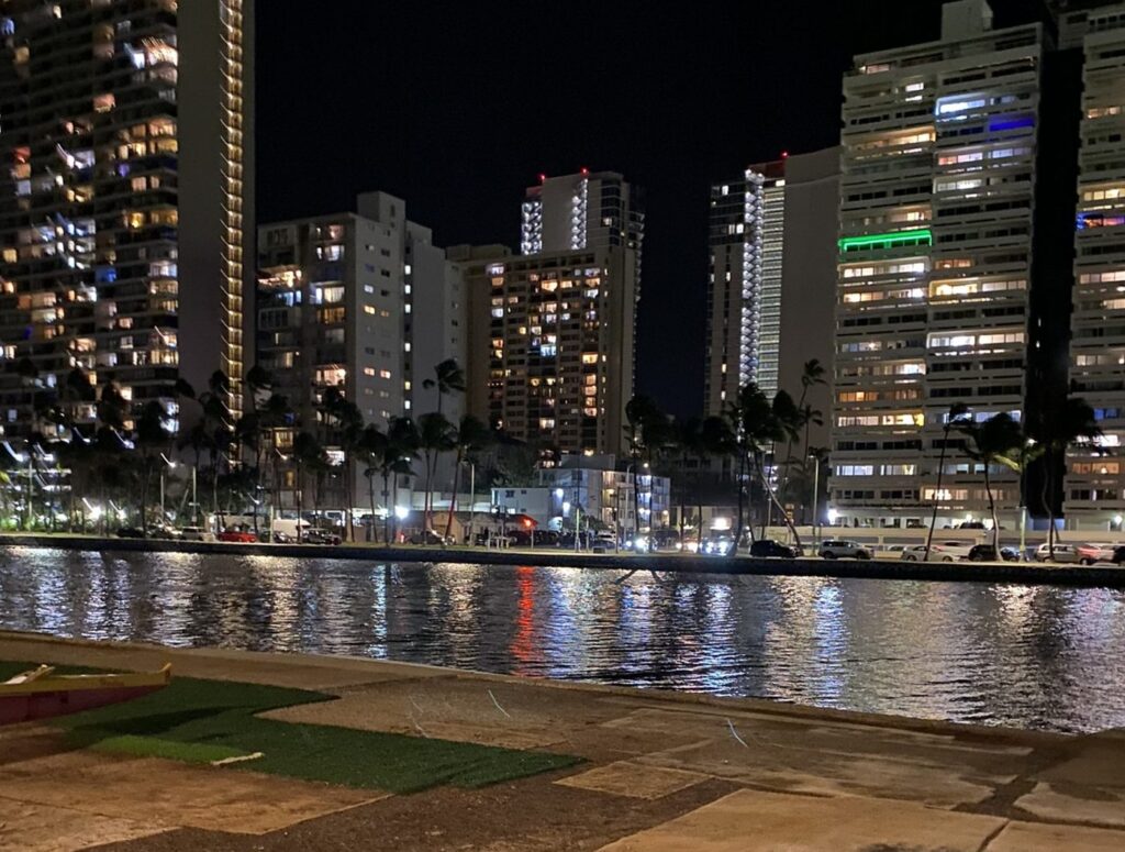 Cars parked along Ala Wai Boulevard at night, across the Ala Wai Canal from the Waikiki side