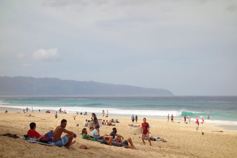 Spectators on the sand at Ehukai Beach watching waves break at the Banzai Pipeline on Oahu's North Shore