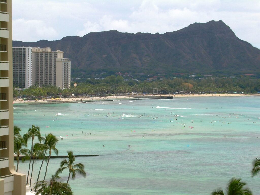 Diamond Head above the turquoise water and surfers of Waikiki, seen from a hotel balcony