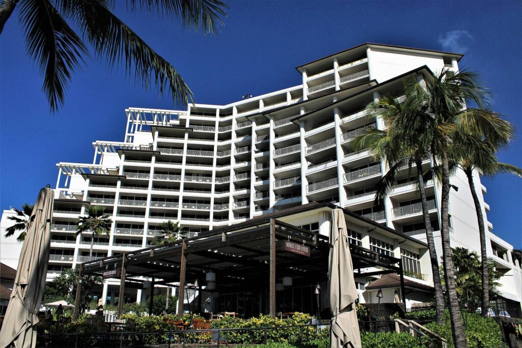 The terraced white towers of the Four Seasons Resort Oahu at Ko Olina behind palm trees