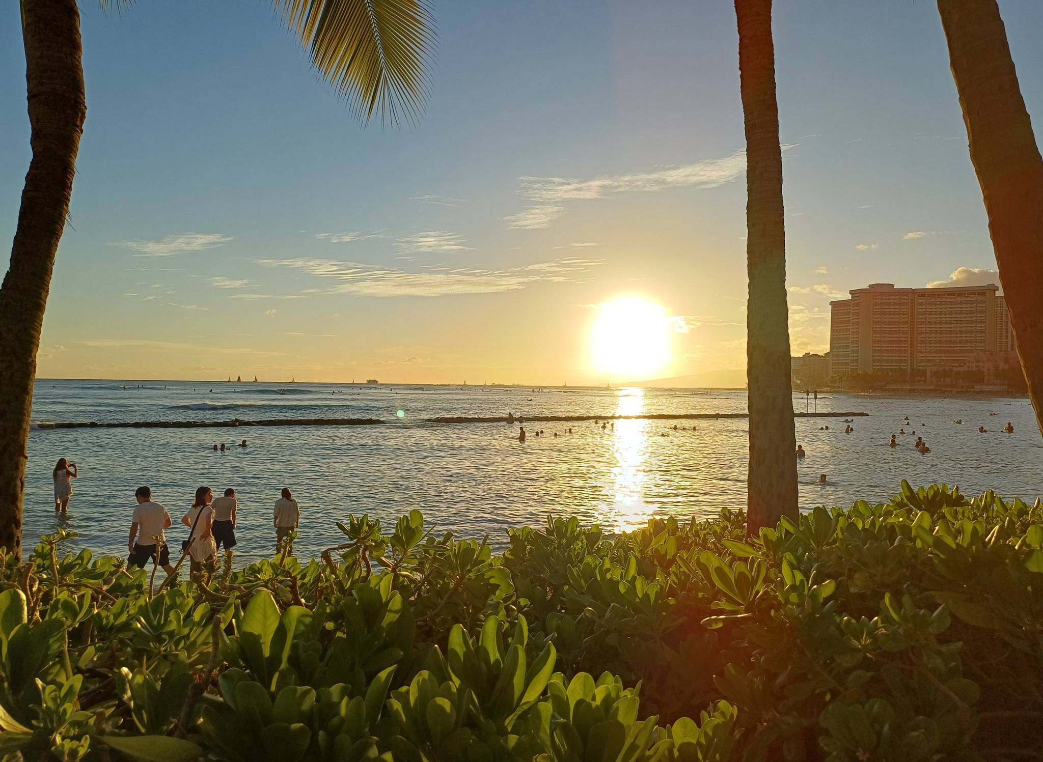 People watching the sun set over the water from Kuhio Beach Park in Waikiki, one of the best free things to do in Waikiki