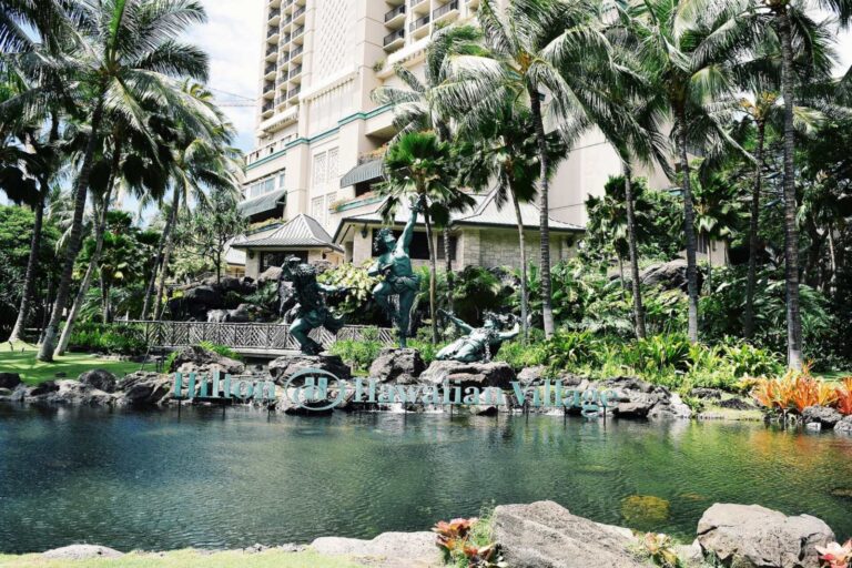 The Hilton Hawaiian Village sign beside a pond on the resort grounds