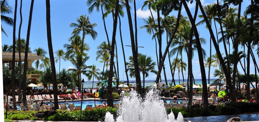 Palms, a fountain and a pool at Hilton Hawaiian Village in Waikiki, with the ocean behind