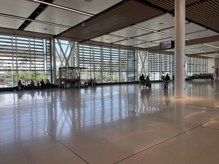 Bright concourse at Honolulu airport with a wood-slat ceiling and louvered glass wall