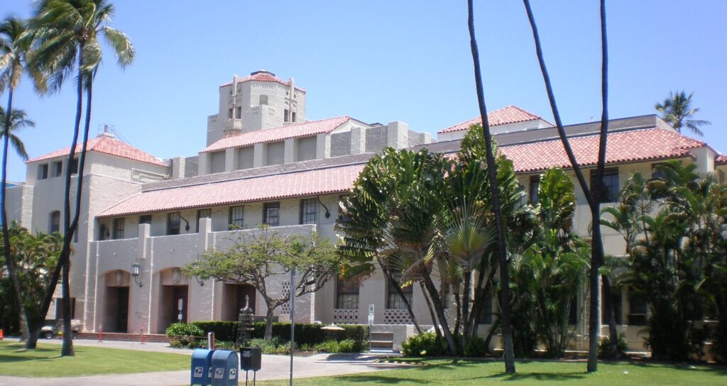 Honolulu Hale, Honolulu's city hall, a cream building with red tile roofs behind palm trees