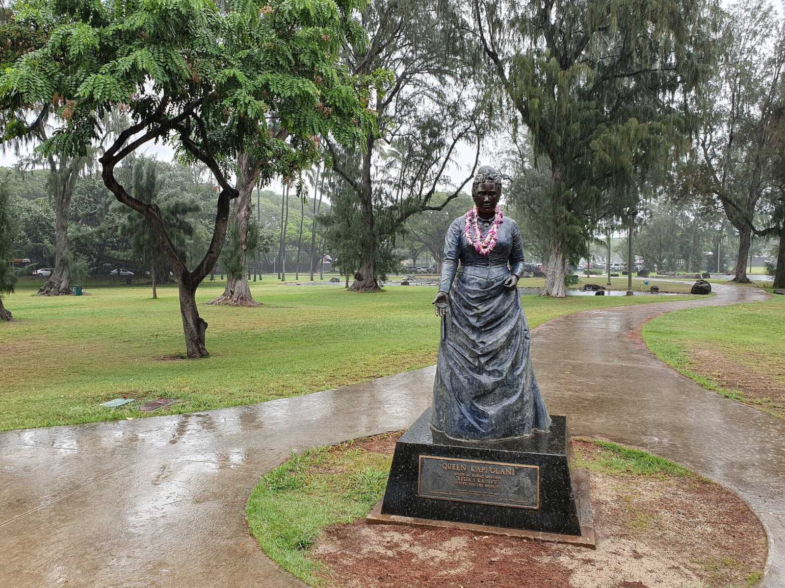 A bronze statue on a path through the lawns and shade trees of Kapiolani Park in Waikiki