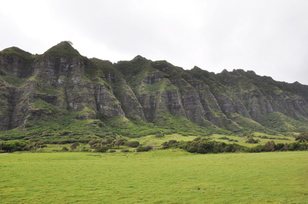 Green cliffs above open pasture at Kualoa Ranch on Oahu's windward side