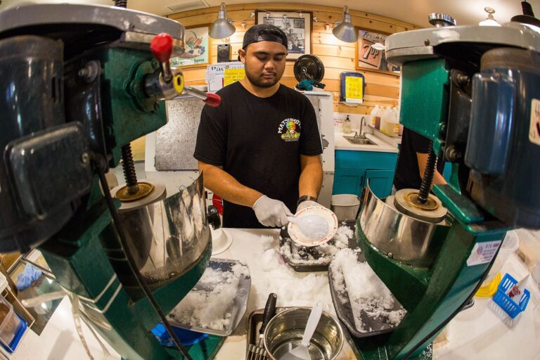 A worker shaping ice between shave ice machines at Matsumoto