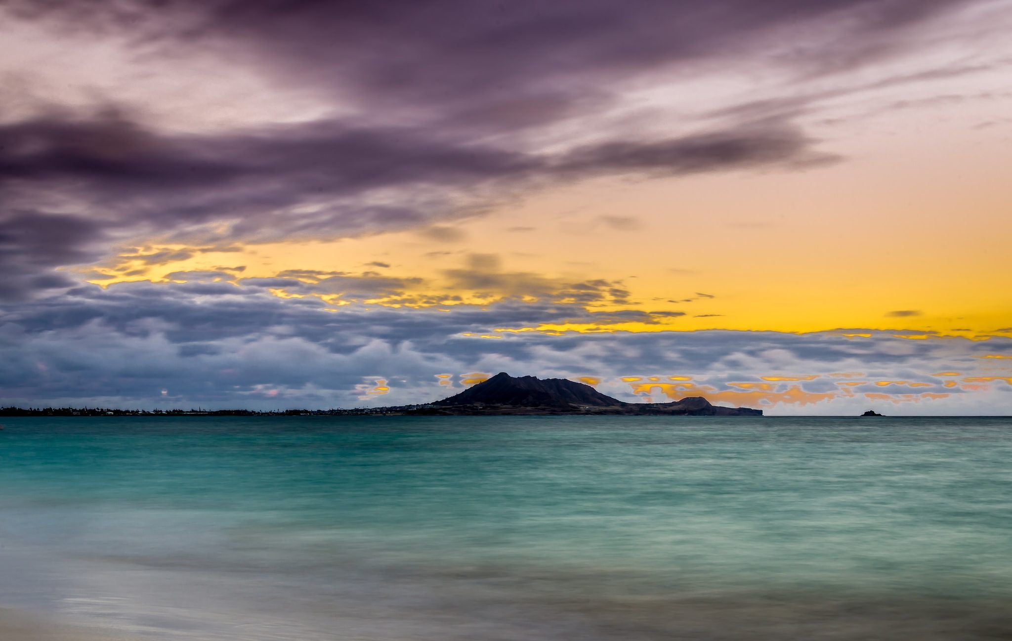 Sunset clouds in gold and violet over calm turquoise water at Kailua Beach on Oahu