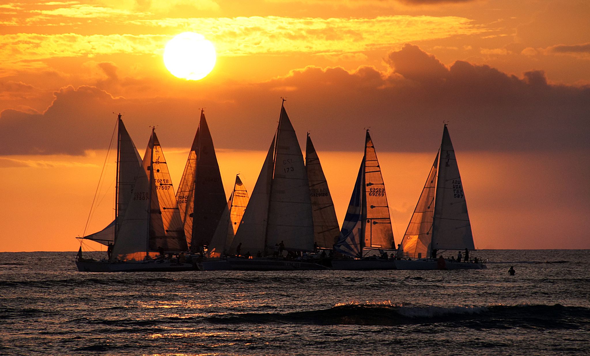 Sailboats silhouetted against the setting sun off Waikiki Beach, the view from a Waikiki sunset cruise
