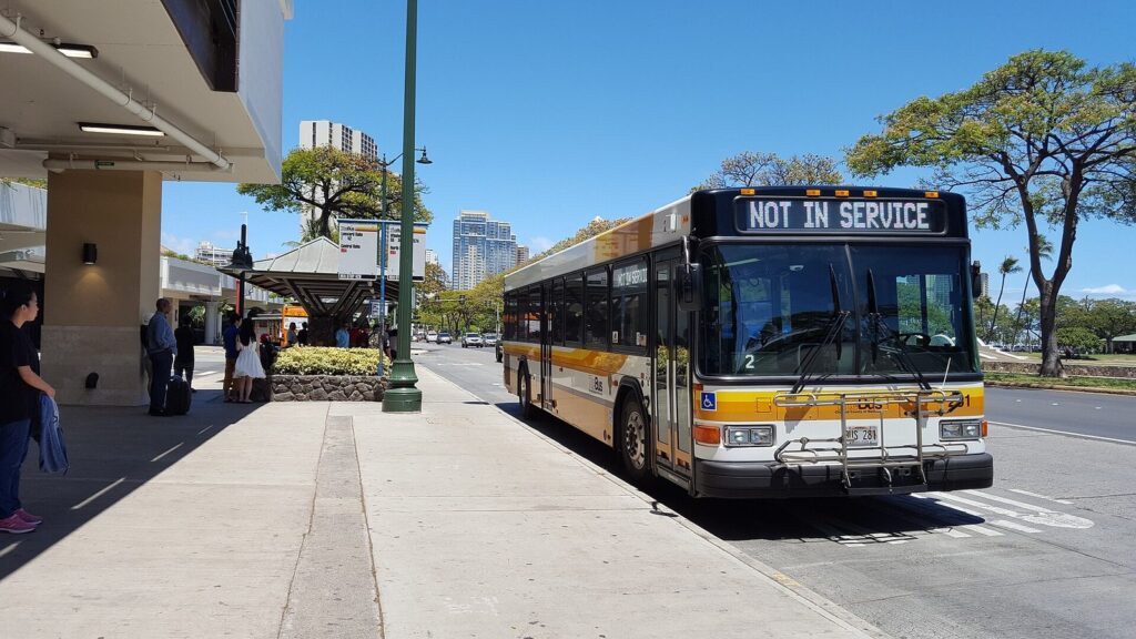 A yellow and white TheBus coach pulled up at a covered bus stop in Honolulu