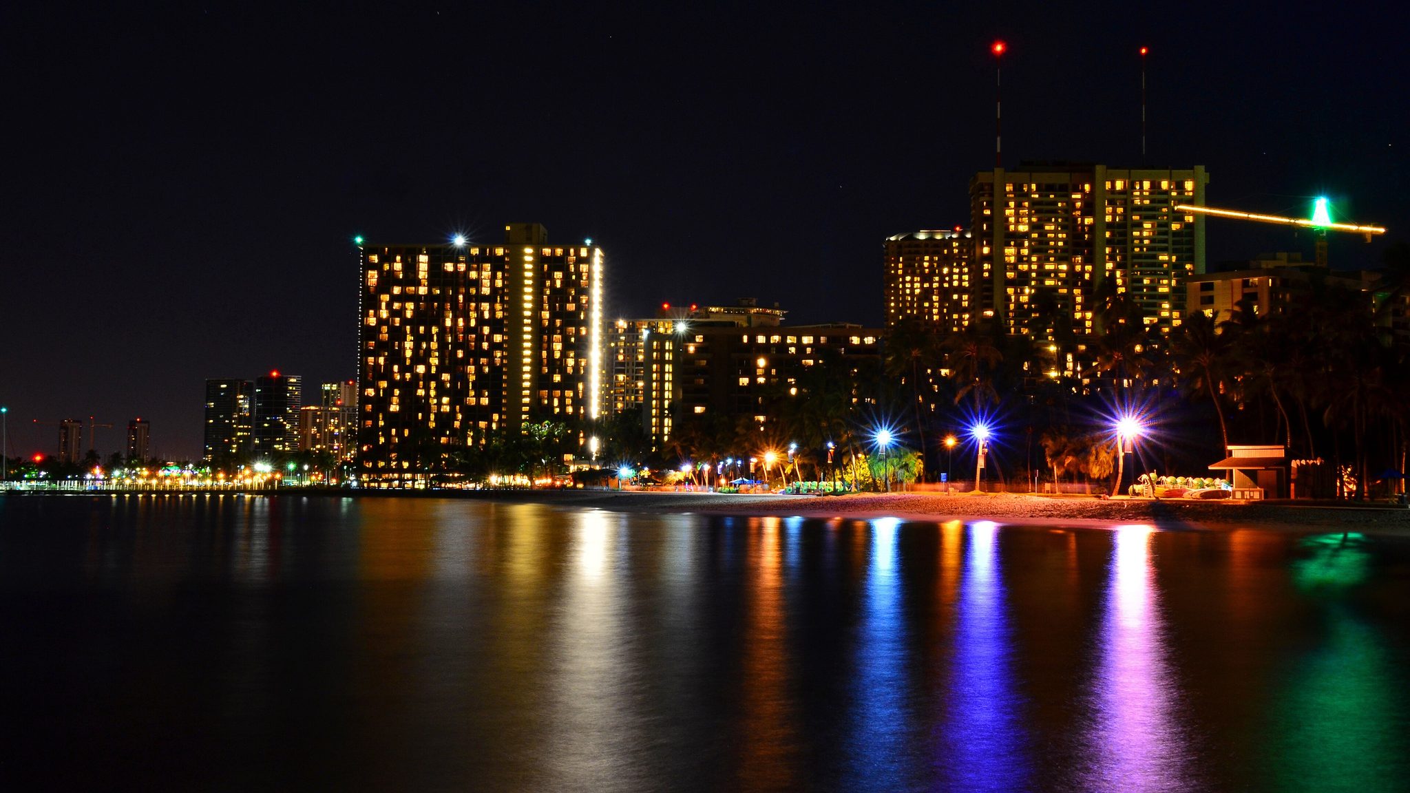 The Waikiki skyline lit up at night along the water, things to do in Waikiki after dark