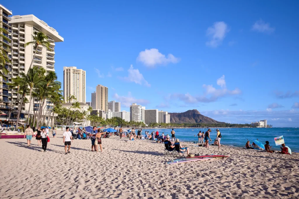 Waikiki Beach looking east toward Diamond Head, with hotels, palms and beachgoers on the sand