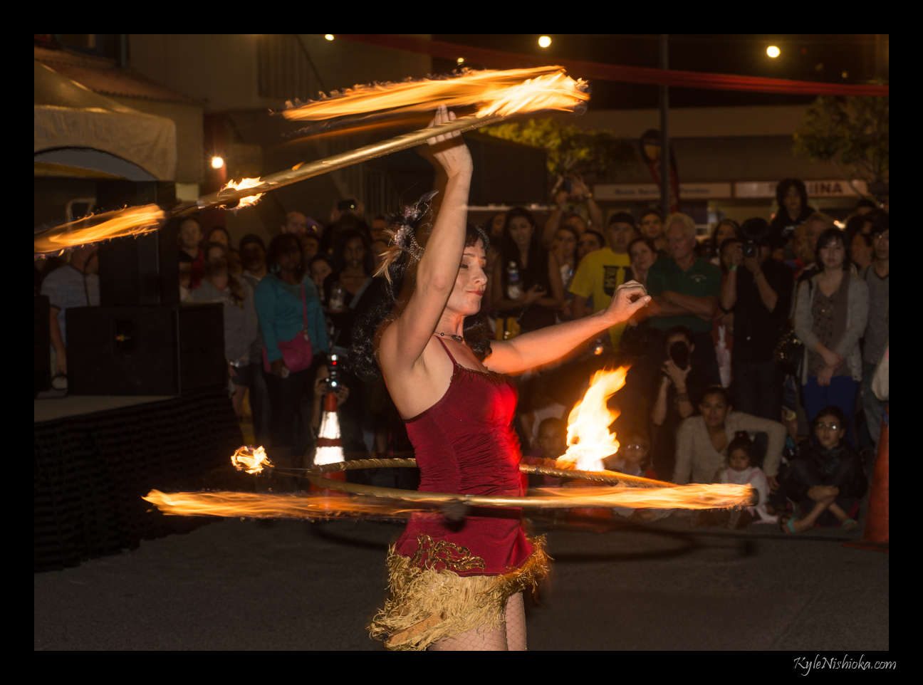 A fire dancer spinning flaming hoops in front of a crowd at the Honolulu Night Market