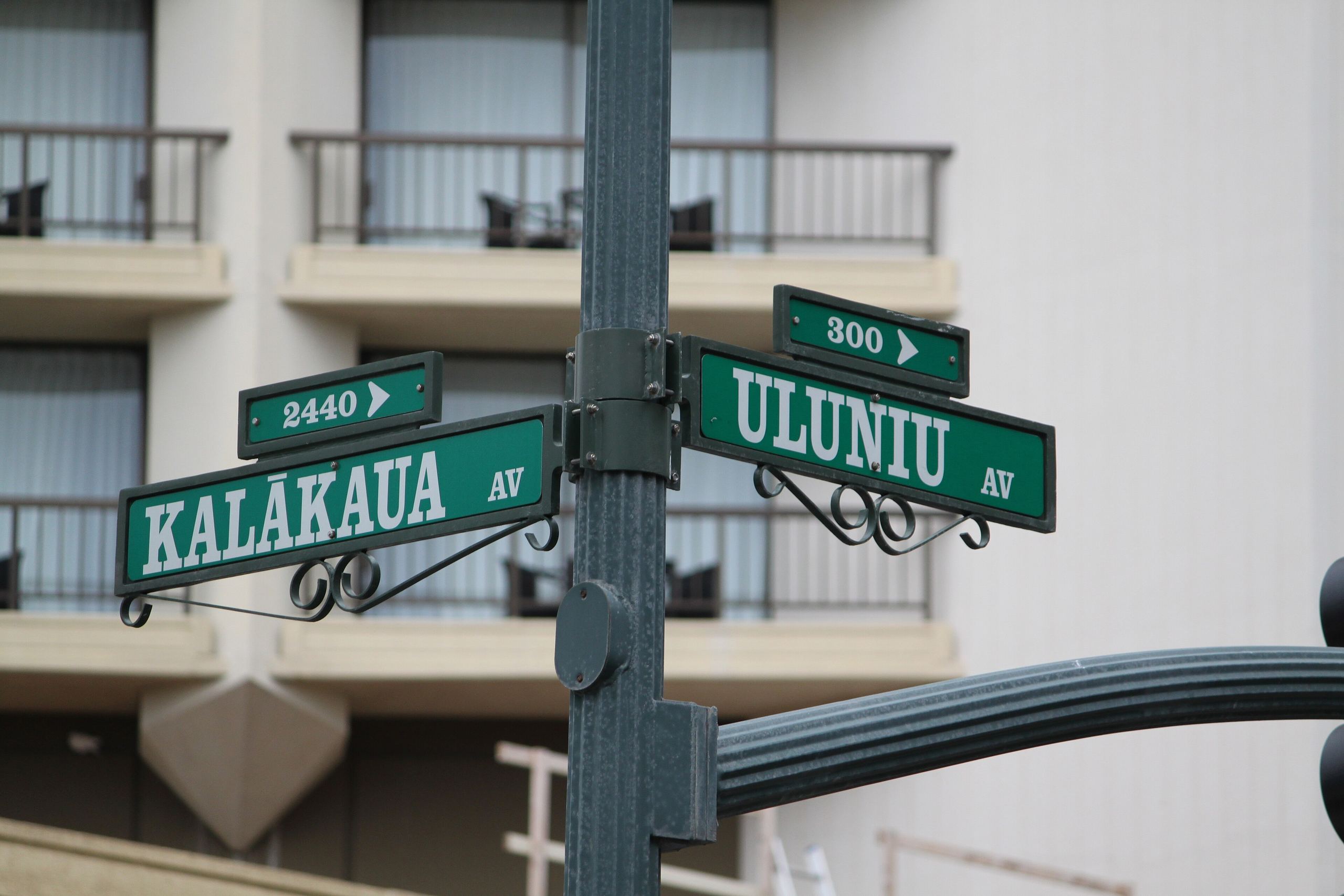 Green street signs for Kalākaua Avenue and Uluniu Avenue in Waikiki, with a kahakō over the second a in Kalākaua