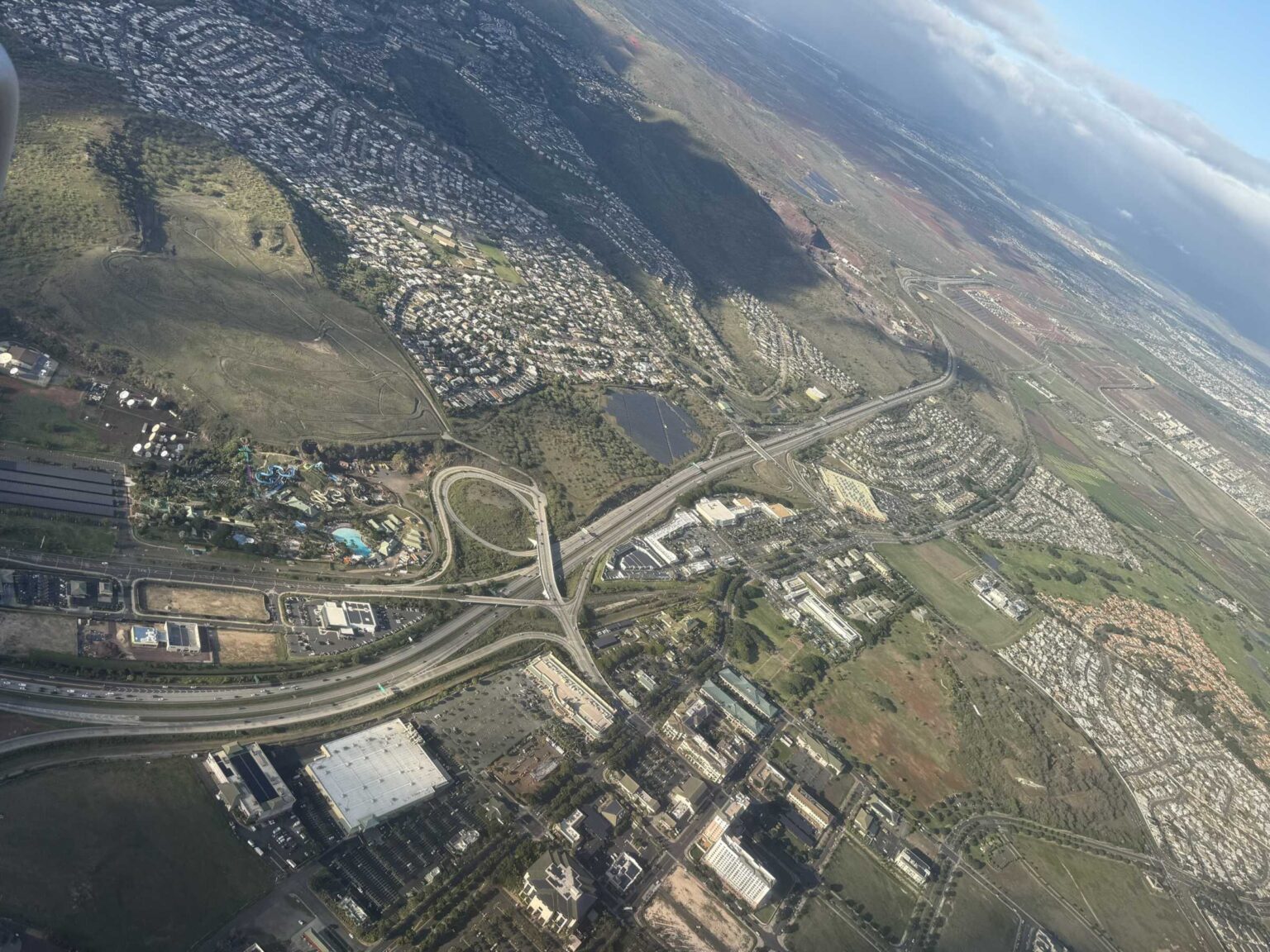 Aerial view of Kapolei, Oahu, with the H-1 ending at a water park, Costco and shopping centers below