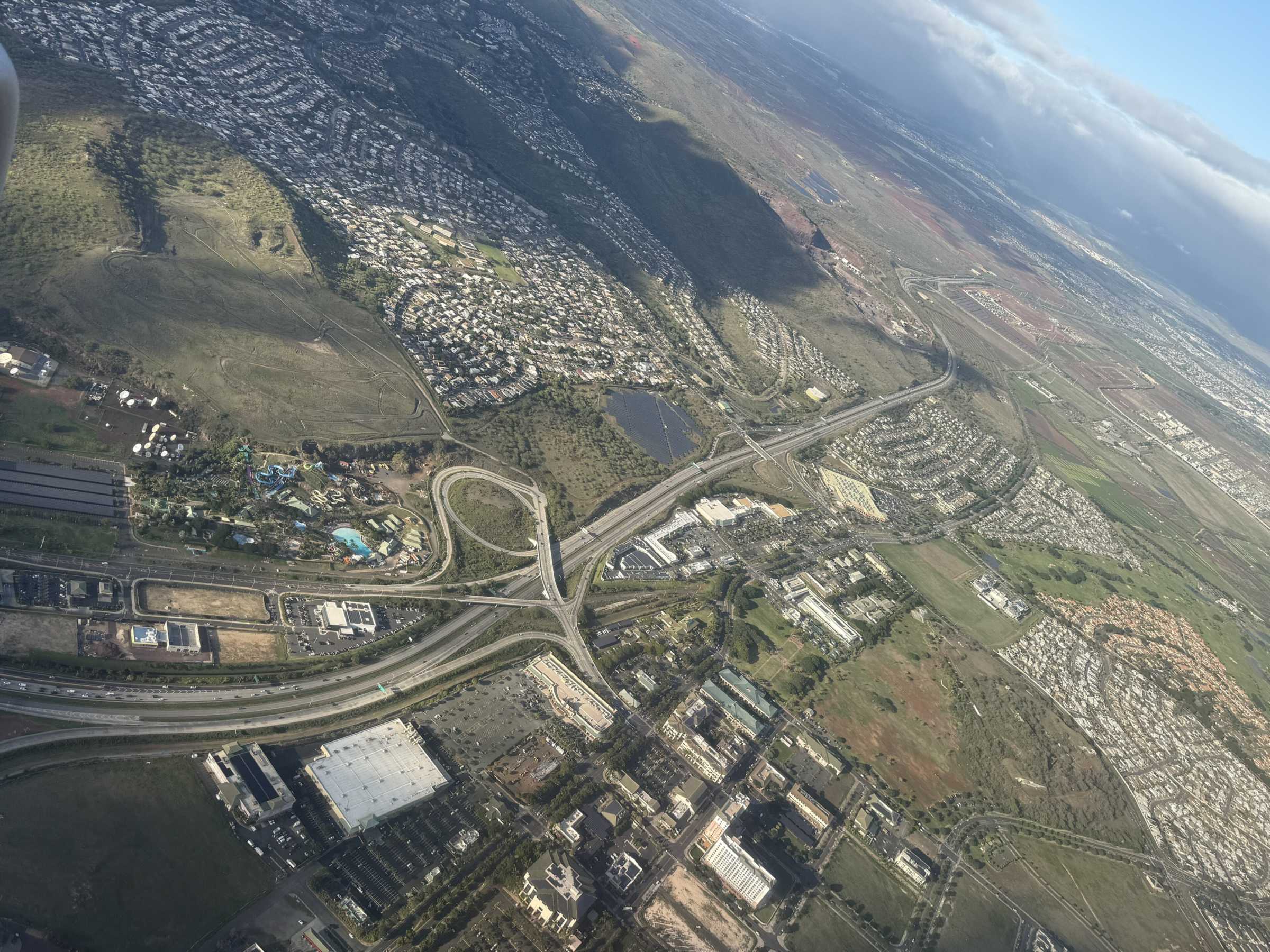 Aerial view of Kapolei, Oahu, with the H-1 ending at a water park, Costco and shopping centers below