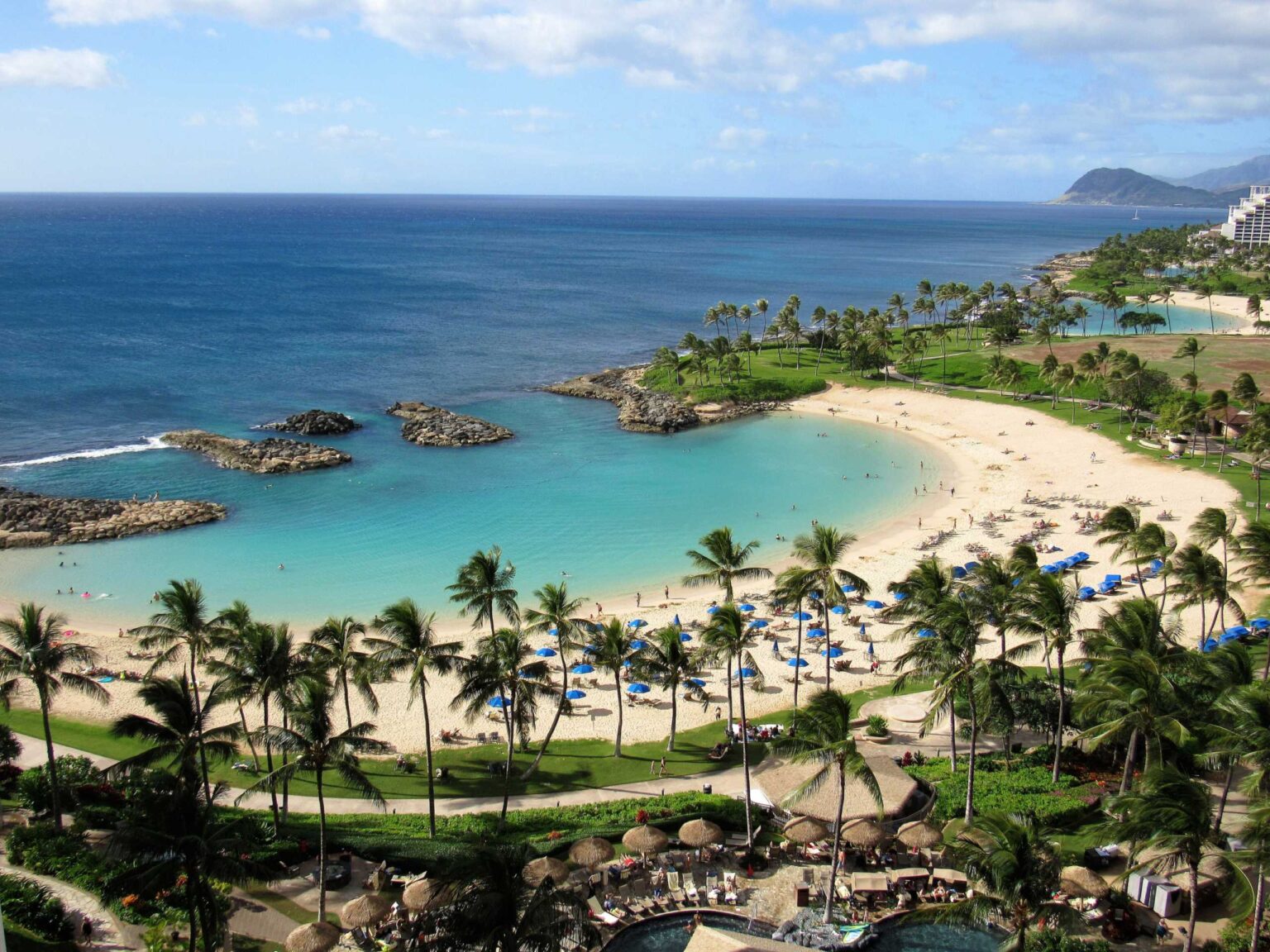 A Ko Olina lagoon with pale sand, turquoise water and rock breakwaters at its mouth