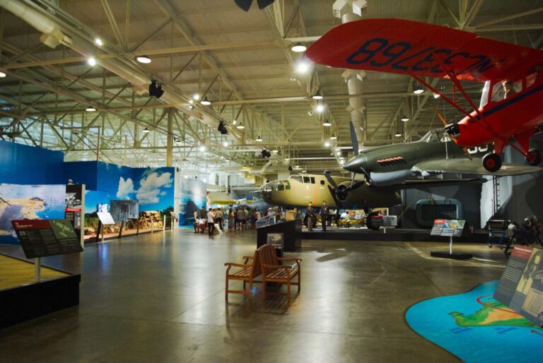 Visitors walking through Hangar 37 at the Pearl Harbor Aviation Museum, with a B-25 and a P-40 under a steel roof