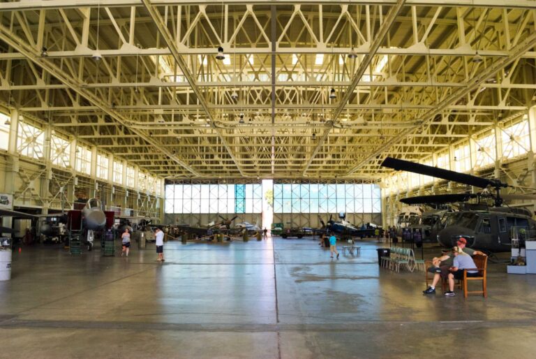The steel-framed interior of Hangar 79 with its glass end wall, a jet and helicopters