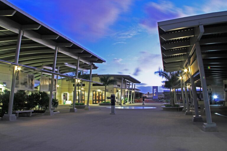 The Pearl Harbor Visitor Center courtyard at dusk, with covered walkways and palms