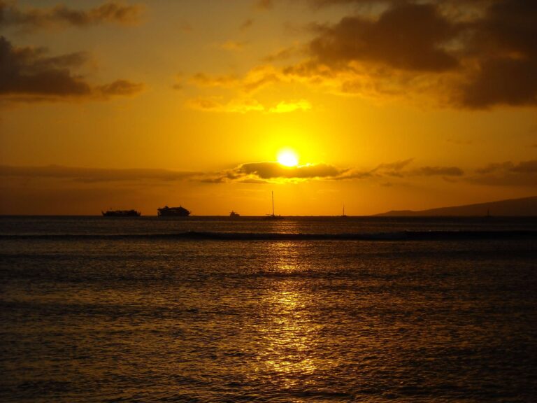 The sun setting over the water off Queen’s Surf Beach, with boats on the horizon