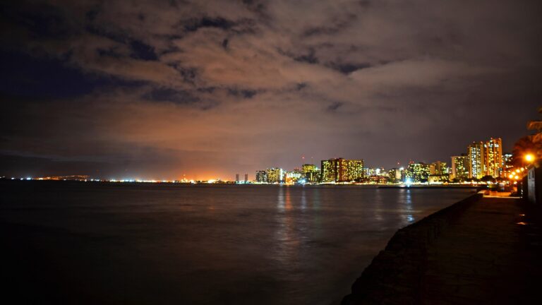 Rain clouds over the Waikiki skyline and the ocean at night