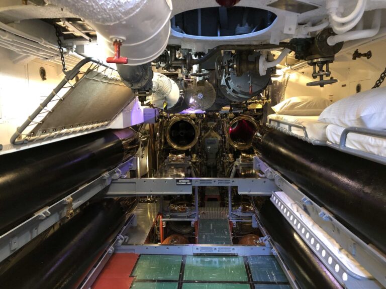 The forward torpedo room of the USS Bowfin, with torpedoes and bunks in a narrow passage
