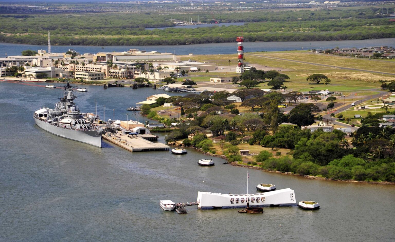 Aerial view of Pearl Harbor with the Battleship Missouri Memorial at Ford Island at left and the USS Arizona Memorial at right